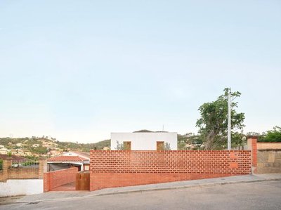 The image showcases a modern residential building with a striking brick facade. The brickwork is per