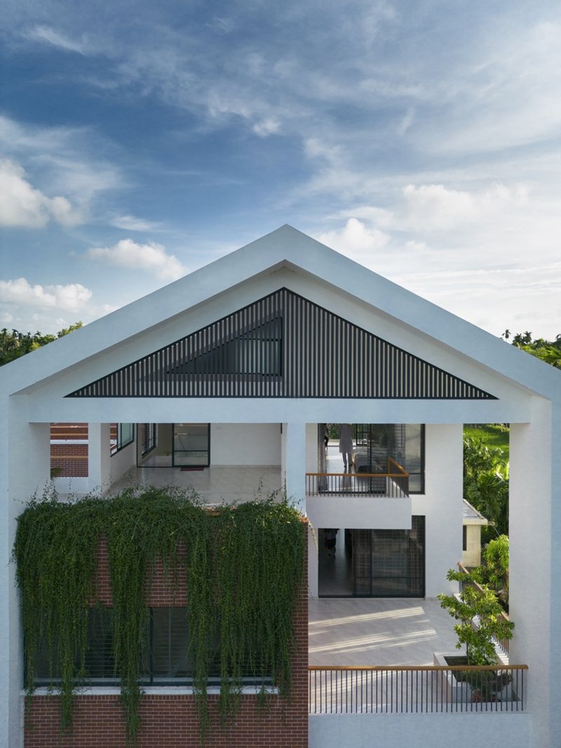 White gable frame enclosing a dark corrugated panel with brick and green climbing vines below