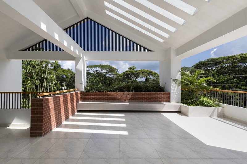 Rooftop terrace with brick planters and striped ceiling vents framing views of mature trees