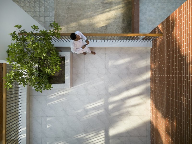 Overhead view of the courtyard with large stone pavers and a figure in white descending the stair