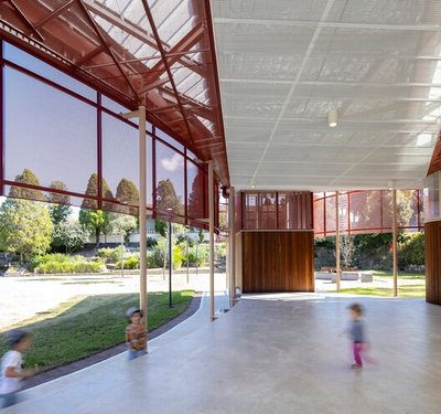 This architectural image showcases a modern pavilion structure within a park setting. The design fea