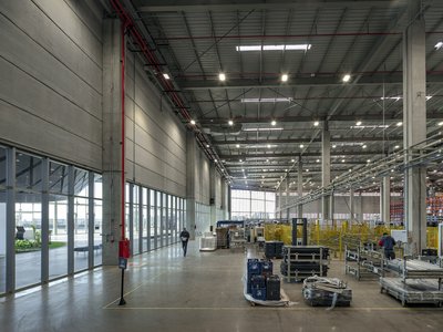 This architectural image showcases the interior of a large industrial warehouse or factory. The spac