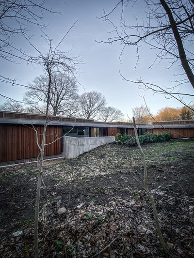 This architectural image showcases a modern, earth-sheltered residence with a wood facade and concre