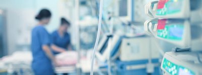 The image depicts a hospital room, likely an intensive care unit, featuring medical equipment and nu