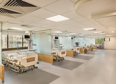 This architectural image showcases a modern hospital room with multiple patient beds separated by gl
