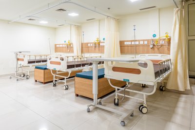 This image showcases a modern hospital room with multiple patient beds. The room features a clean an