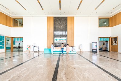 This is a photograph of a modern hospital lobby featuring a spacious and well-lit reception area. Th