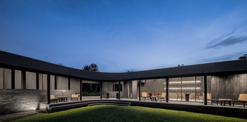 Dusk view across the central grass courtyard to the illuminated cafe dining room