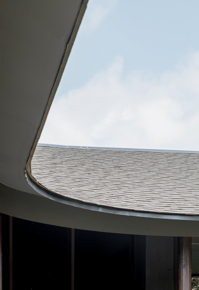 Looking up at a curved folded roof edge meeting the tiled pitched roof