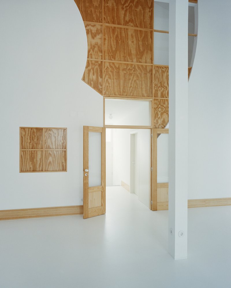 Interior view with a curved plywood-clad ceiling soffit and a thin white pillar dividing the space