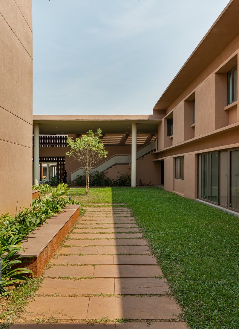 Secondary courtyard with a sandstone paver path and a young tree between the ward volumes