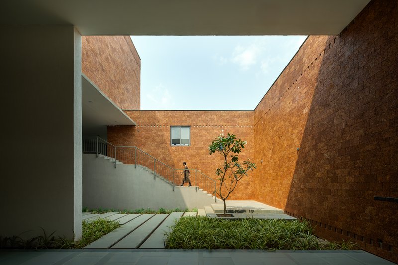 Sunken stair court surrounded by laterite brick walls with a single young tree