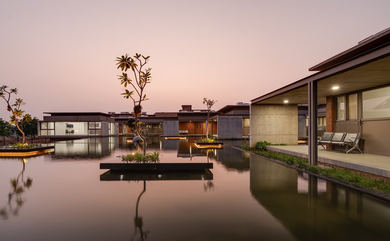 Dusk view of the ward complex mirrored in a calm reflecting pool with floating planters
