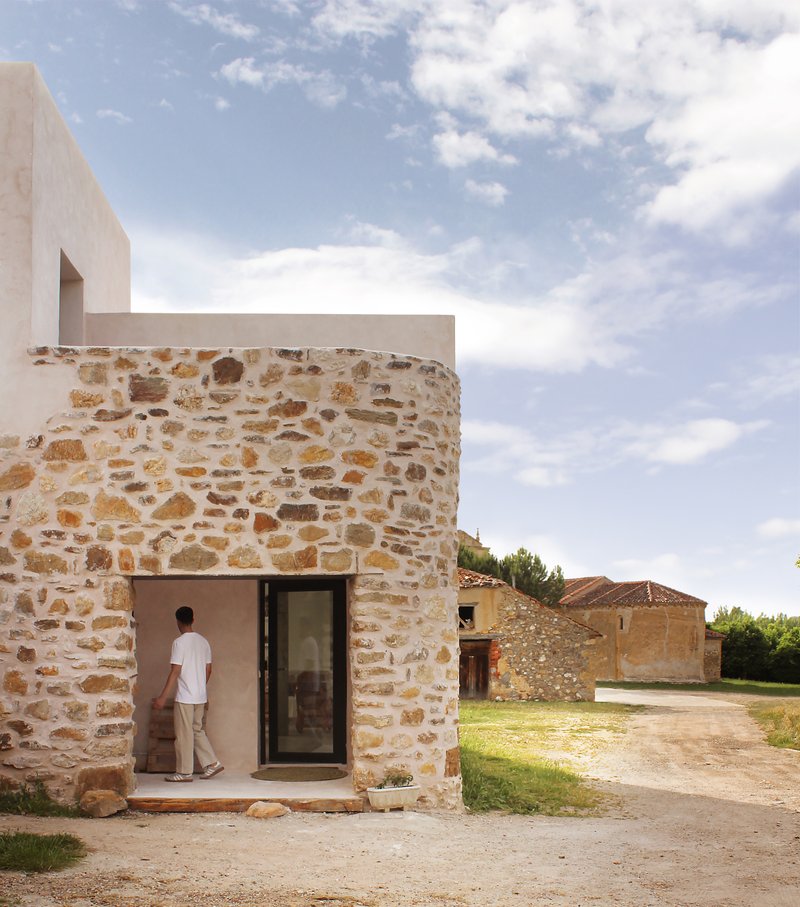 Curved stone wall and entrance door at the corner of the converted stable