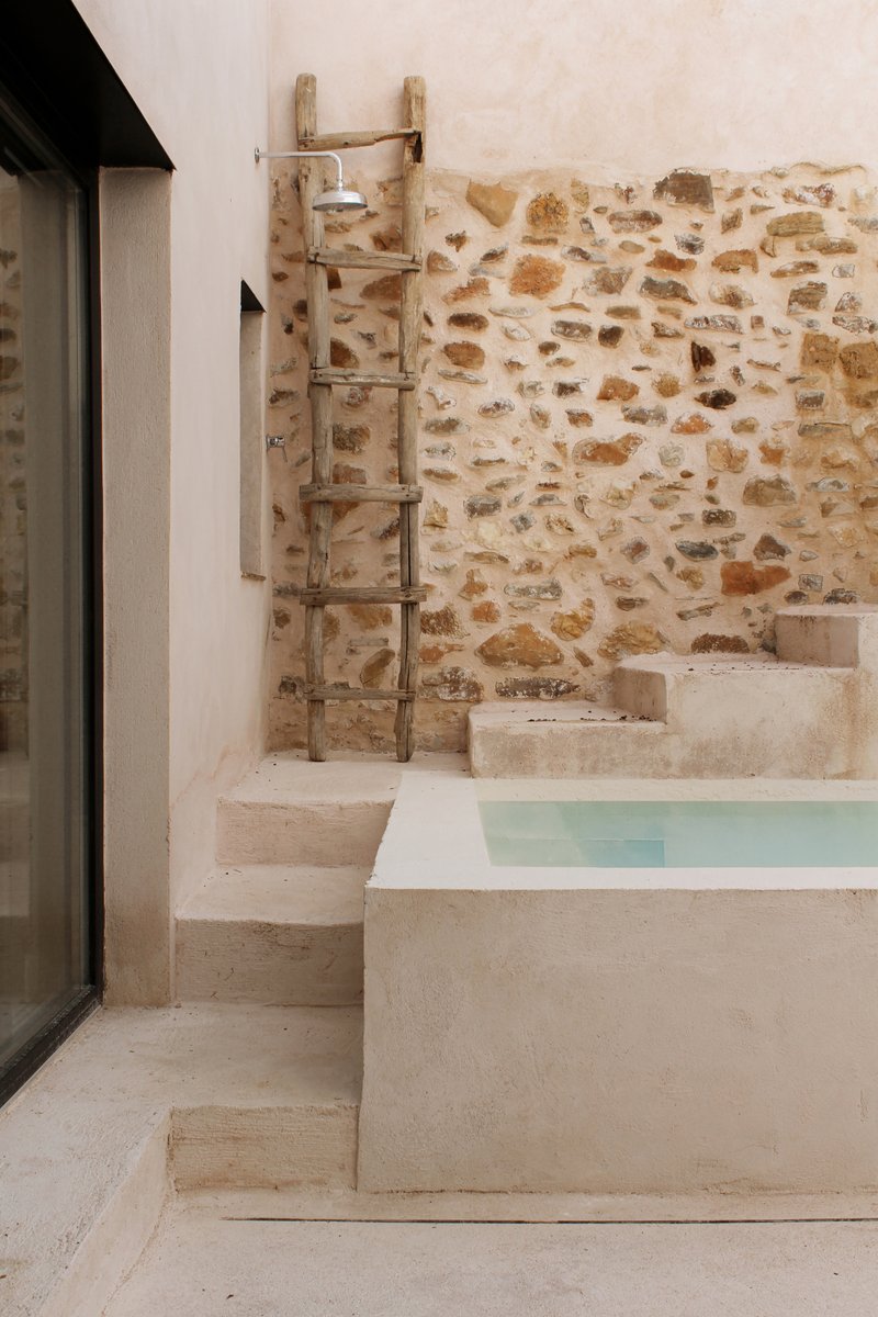 Detail of the courtyard pool with an outdoor shower against the stone wall