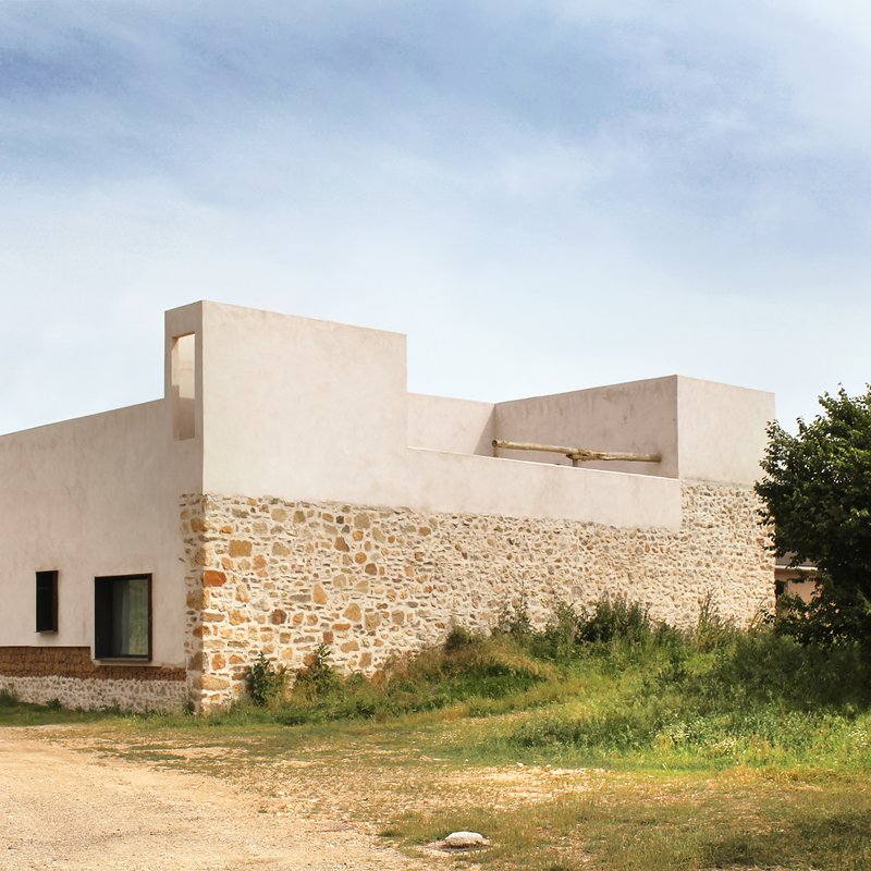 Side view of the house showing the new plaster volume above the original stone enclosure