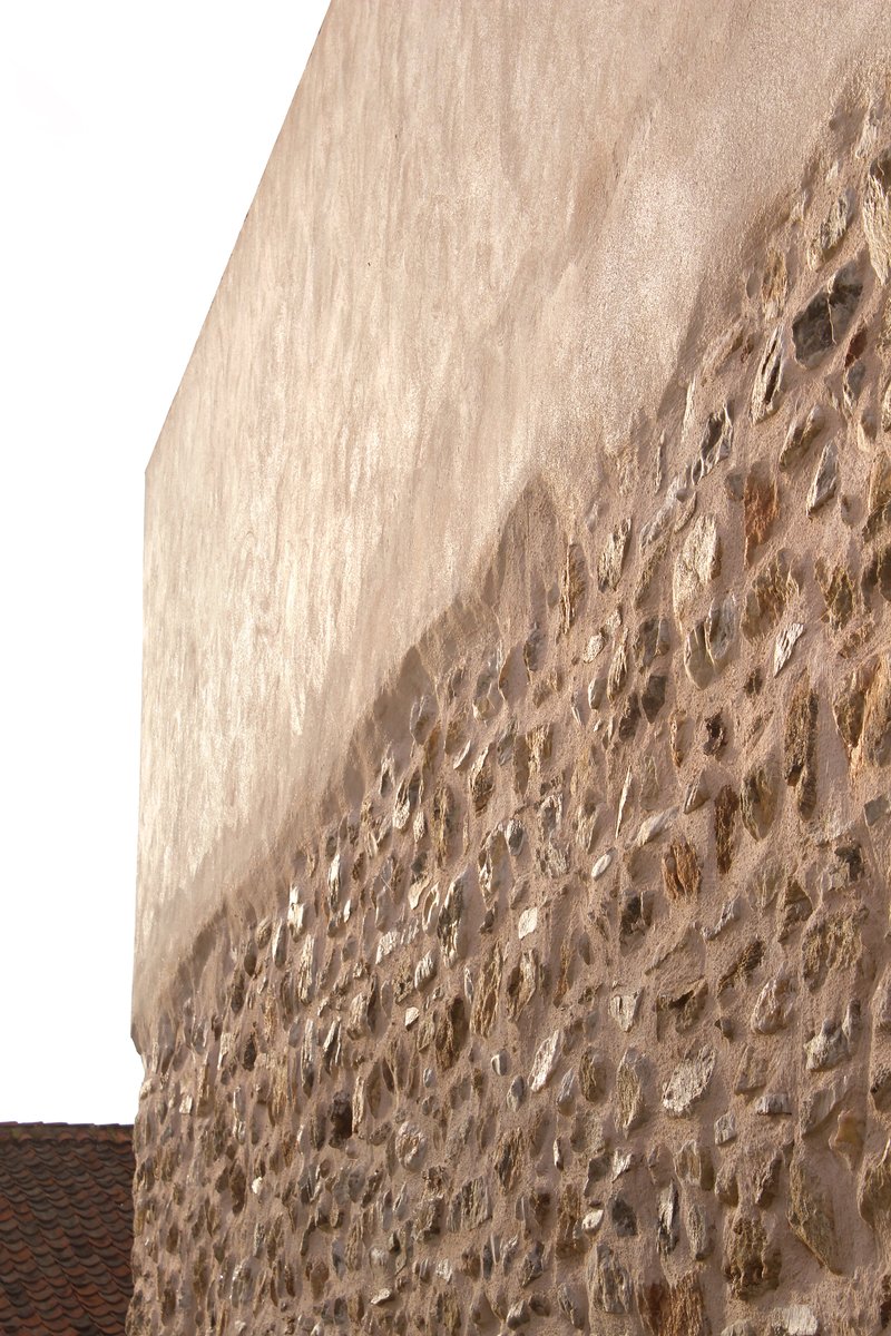 Close-up of the rough stone wall meeting the smooth white plaster cap