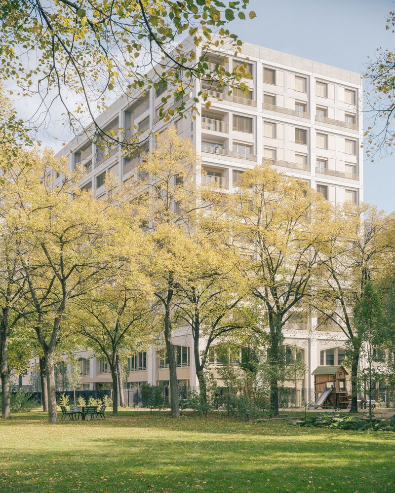 View of the social housing block from the central park through a row of yellow-leaved trees