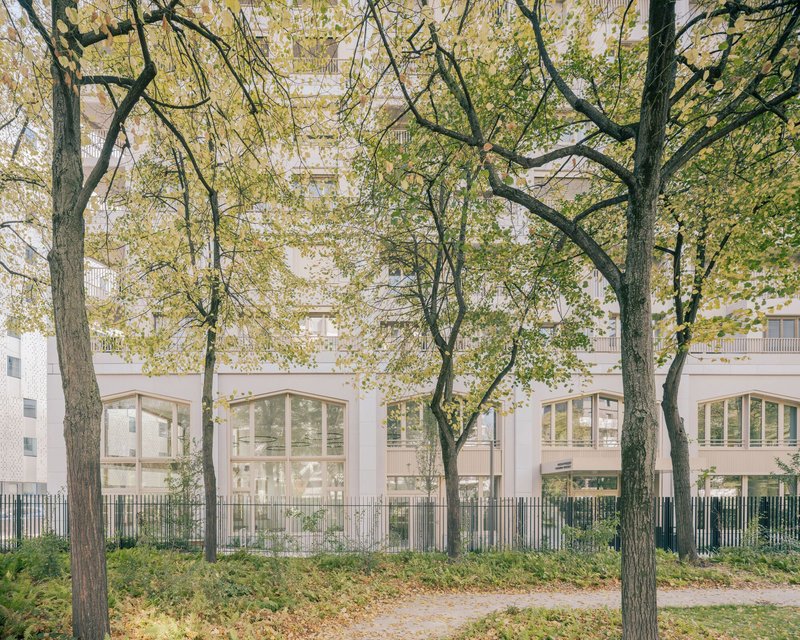 Pale facade of an existing tower seen behind mature trees on the ZAC site
