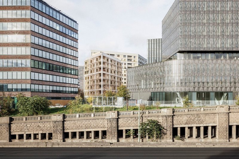 Wider city view showing the media library's perforated metal facade behind the boulevard wall