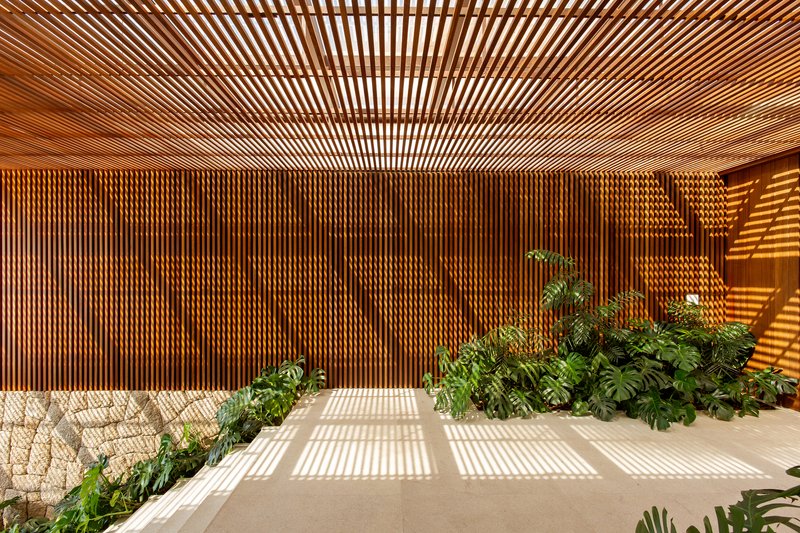 Cross-section view of the slatted timber wall and ceiling casting striped shadows over the stone floor