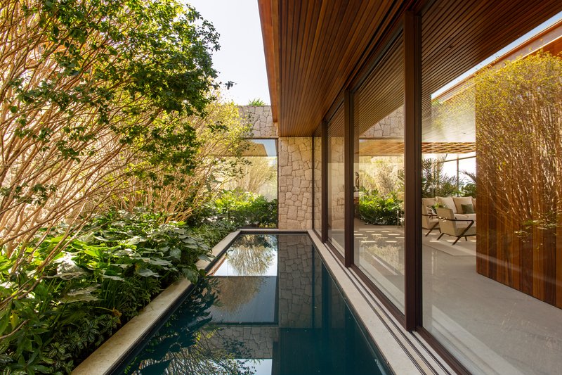 Narrow reflecting pool tucked between the stone wall and a glazed side elevation