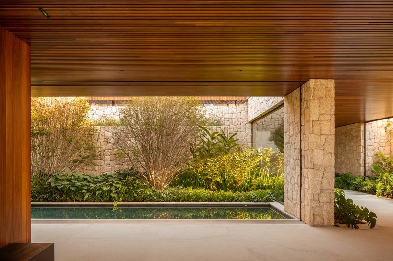Interior reflecting pool along a rough stone wall under a timber ceiling