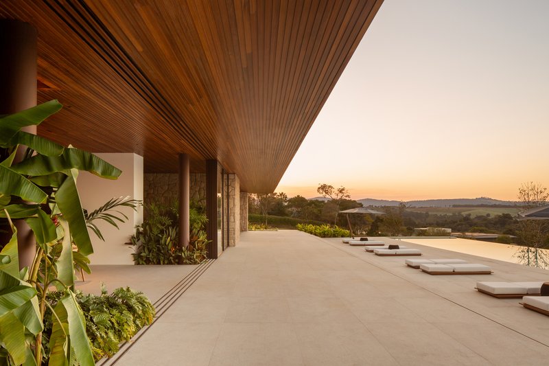 Covered veranda at sunset looking along the pool deck with lounge cushions and the timber slatted ceiling above