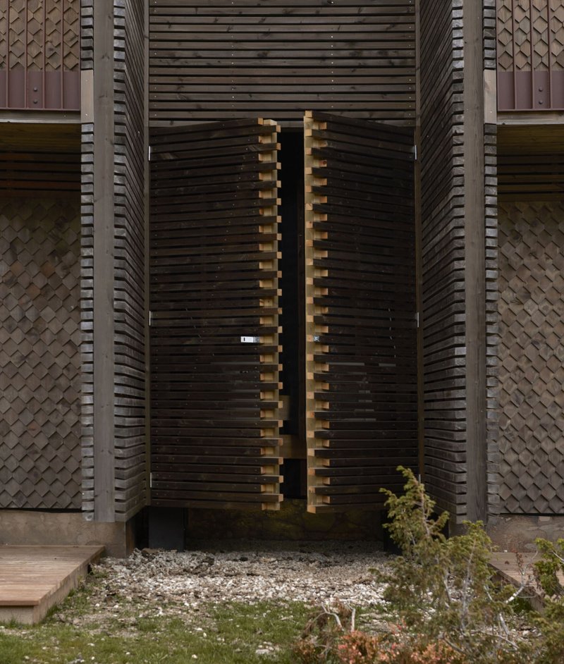 Entry gate: slatted timber screen doors set within the facade depth